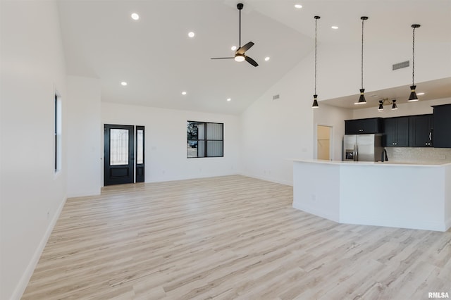 kitchen featuring high vaulted ceiling, dark cabinetry, stainless steel refrigerator with ice dispenser, and visible vents