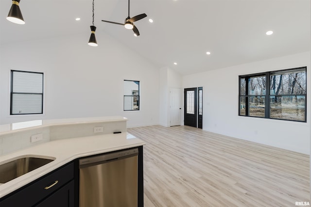 kitchen with open floor plan, light countertops, stainless steel dishwasher, dark cabinetry, and light wood-type flooring