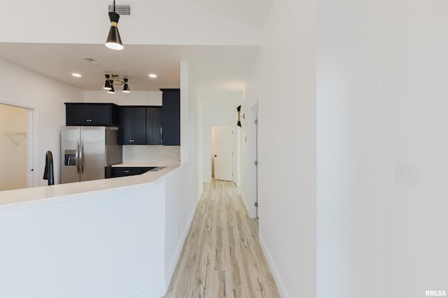 kitchen featuring visible vents, light countertops, dark cabinetry, stainless steel refrigerator with ice dispenser, and decorative backsplash