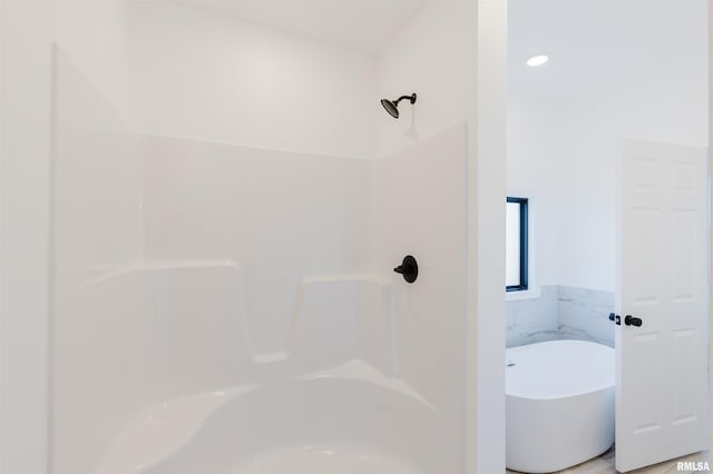 bathroom featuring walk in shower, a freestanding tub, and tile walls