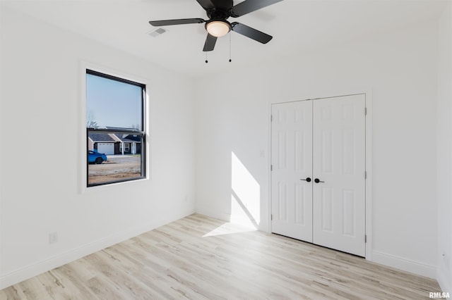 spare room featuring light wood-style floors, visible vents, ceiling fan, and baseboards