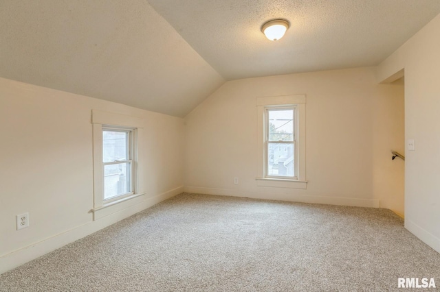 additional living space with lofted ceiling, carpet, and a textured ceiling