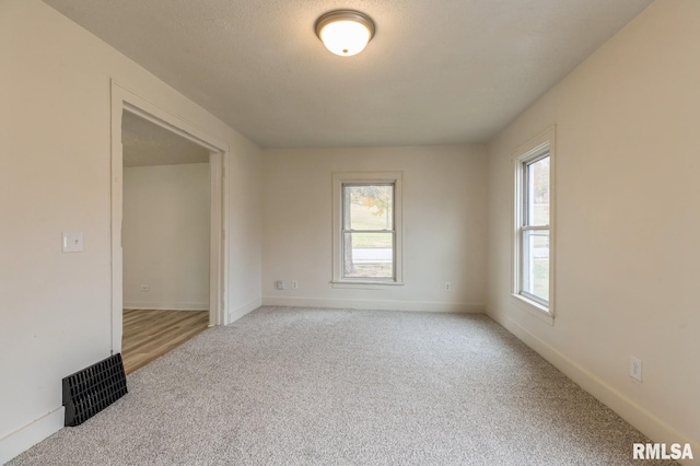 carpeted spare room with a textured ceiling and baseboards