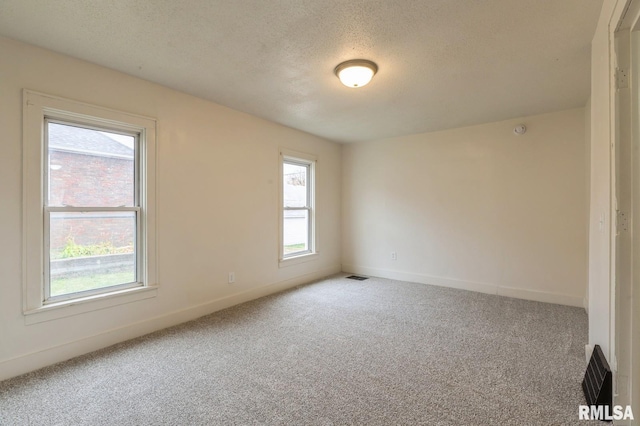 carpeted empty room with baseboards, visible vents, and a textured ceiling