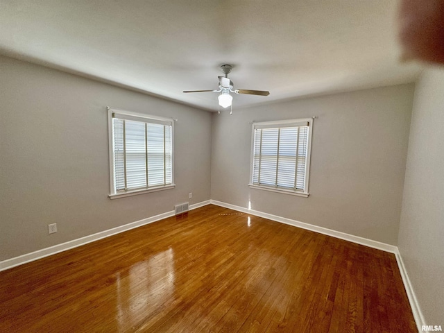 spare room featuring ceiling fan, visible vents, baseboards, and wood finished floors