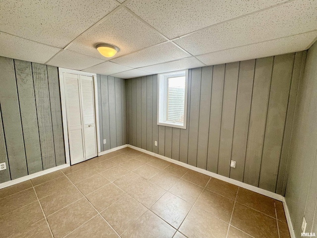 unfurnished bedroom featuring tile patterned flooring, a closet, and a drop ceiling