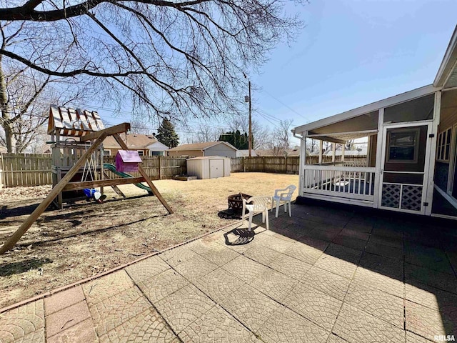 view of patio / terrace with a playground, an outdoor structure, a storage shed, and a fenced backyard