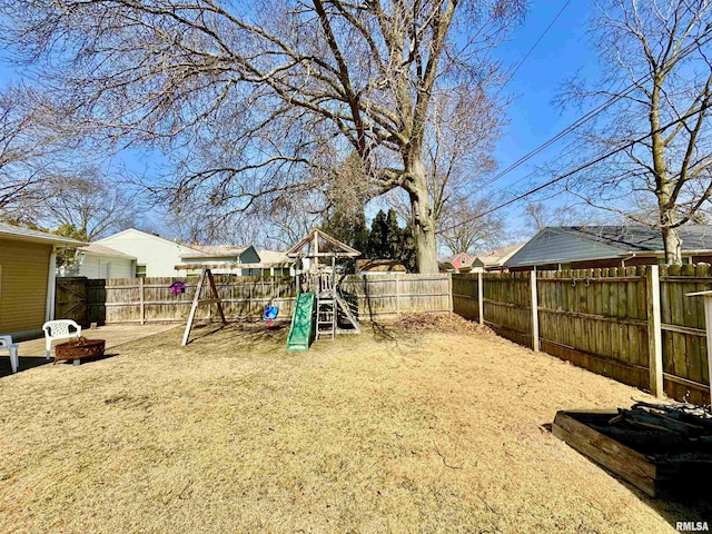 view of yard featuring a fire pit, a playground, and a fenced backyard