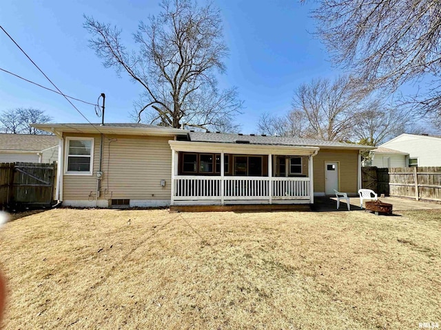 rear view of house featuring a yard, fence, and an outdoor fire pit