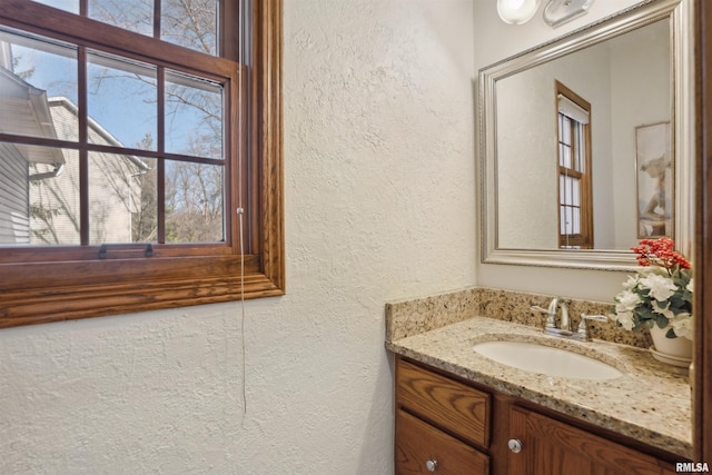 bathroom with a wealth of natural light, vanity, and a textured wall