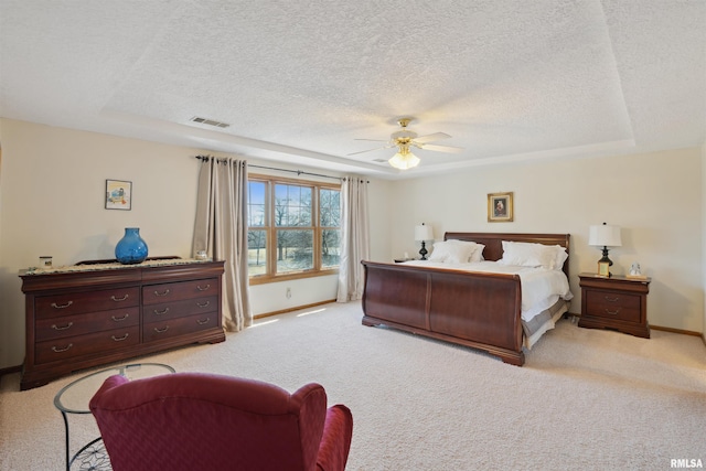 bedroom featuring a raised ceiling, baseboards, visible vents, and light carpet