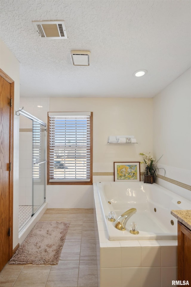 full bathroom featuring visible vents, a shower stall, a jetted tub, tile patterned floors, and a textured ceiling