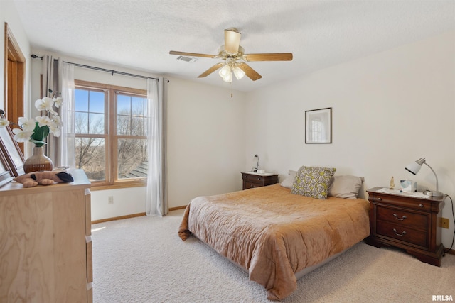 bedroom with visible vents, baseboards, ceiling fan, a textured ceiling, and light colored carpet