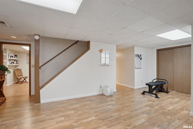 workout area with a drop ceiling, visible vents, light wood-type flooring, and baseboards