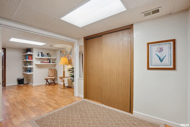 interior space featuring light wood finished floors, visible vents, and a paneled ceiling