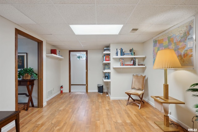 living area featuring visible vents, a paneled ceiling, light wood-type flooring, and baseboards