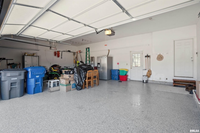 garage featuring a garage door opener and stainless steel fridge with ice dispenser