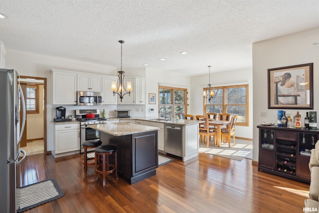 kitchen with a chandelier, white cabinets, stainless steel appliances, and a sink