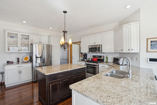 kitchen with dark wood-style flooring, appliances with stainless steel finishes, white cabinetry, and a sink