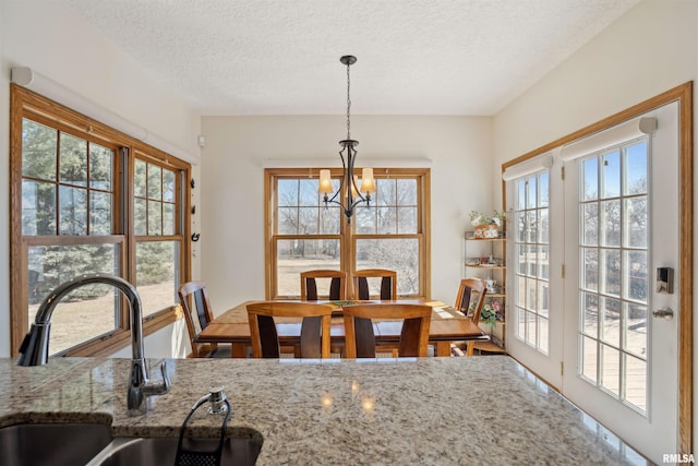 dining room with a notable chandelier, a textured ceiling, and a healthy amount of sunlight