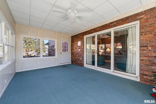 unfurnished sunroom with a drop ceiling and a ceiling fan