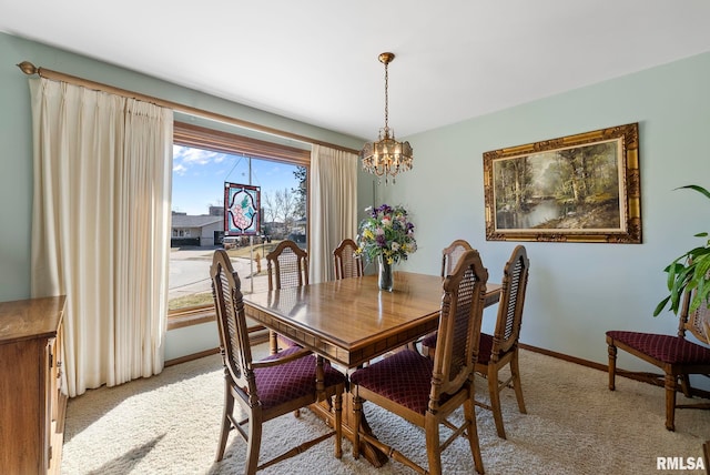 dining space with baseboards, light colored carpet, and a chandelier