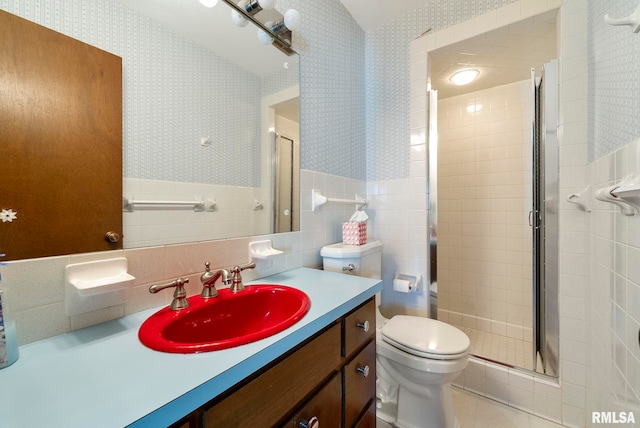 bathroom with a wainscoted wall, toilet, a shower stall, and wallpapered walls