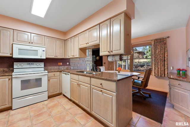 kitchen featuring tasteful backsplash, dark stone countertops, white appliances, and a sink