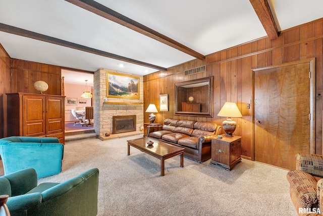 living room featuring wooden walls, visible vents, carpet floors, a stone fireplace, and beamed ceiling