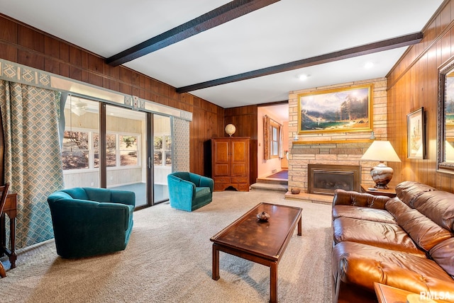 carpeted living room featuring a stone fireplace, beamed ceiling, and wooden walls