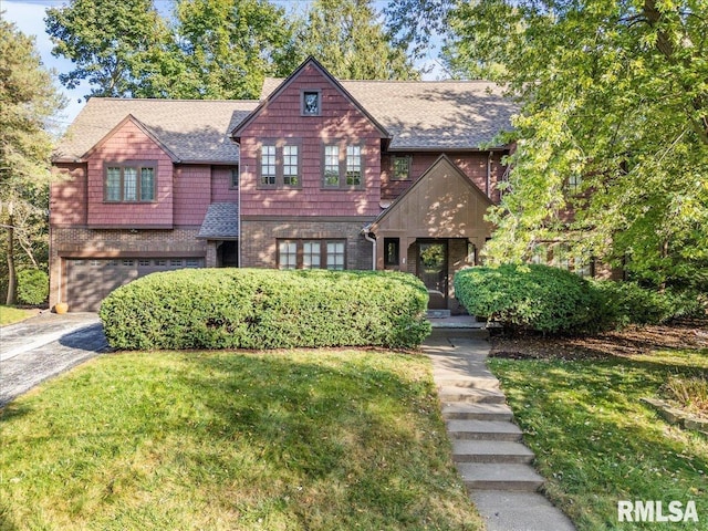 view of front of house with brick siding, a shingled roof, a front yard, a garage, and driveway