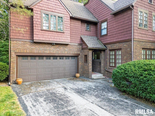 view of front of property featuring aphalt driveway, an attached garage, brick siding, and a shingled roof