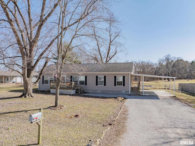 manufactured / mobile home featuring an attached carport, gravel driveway, and fence