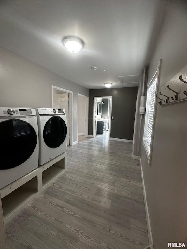 washroom featuring baseboards, attic access, laundry area, wood finished floors, and washer and dryer