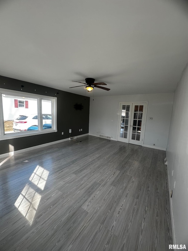 unfurnished living room featuring wood finished floors, visible vents, baseboards, ceiling fan, and french doors