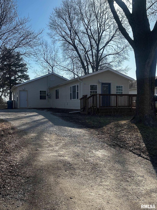 view of front of home with a wooden deck and dirt driveway