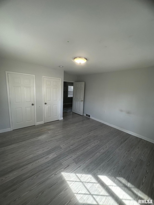 unfurnished room featuring visible vents, baseboards, and dark wood-style flooring