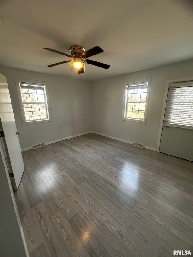 empty room with visible vents, a healthy amount of sunlight, and wood finished floors