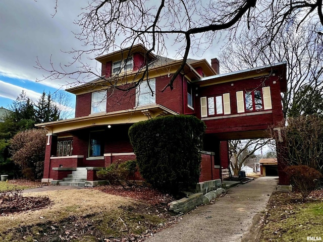 view of front of home with brick siding, a porch, and a chimney