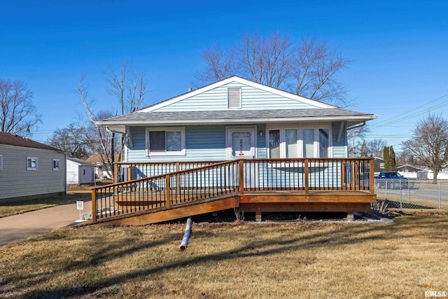 view of front of house featuring roof with shingles, a front yard, and fence