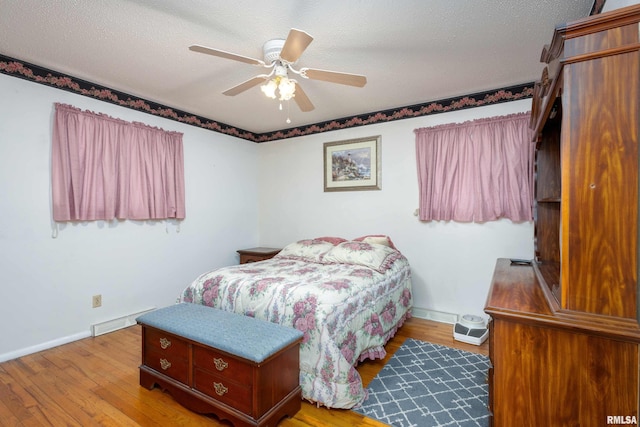 bedroom featuring a ceiling fan, light wood-style floors, baseboards, and a textured ceiling