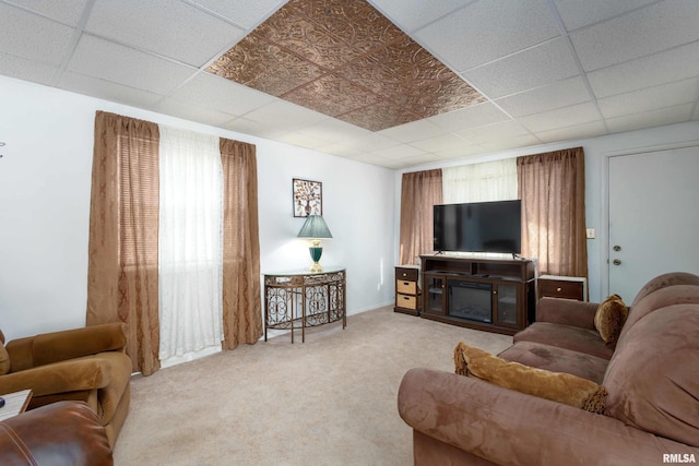 living room featuring a glass covered fireplace, carpet flooring, and a paneled ceiling