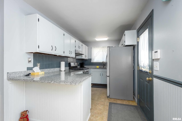 kitchen with tasteful backsplash, under cabinet range hood, appliances with stainless steel finishes, a peninsula, and white cabinetry