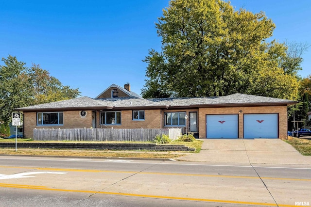 ranch-style house with driveway, a fenced front yard, an attached garage, brick siding, and a chimney