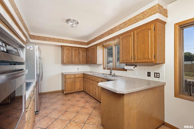 kitchen featuring a sink, backsplash, a peninsula, and light countertops