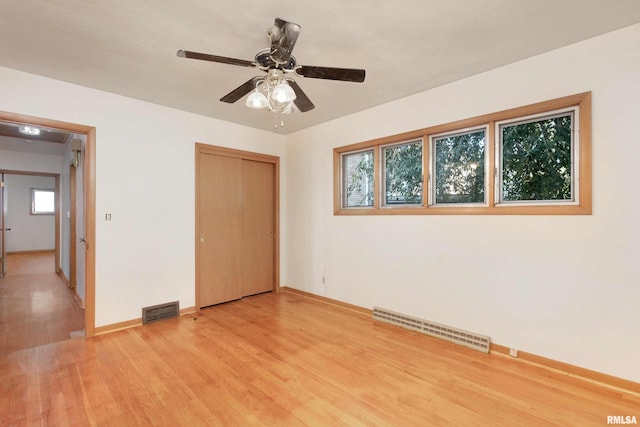 unfurnished bedroom with light wood-type flooring, visible vents, baseboards, and a closet