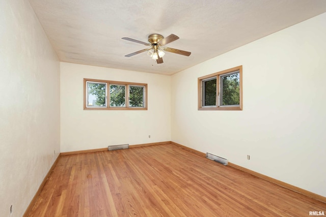 unfurnished room featuring light wood finished floors, visible vents, a ceiling fan, and baseboards