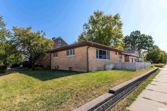 view of home's exterior featuring fence, a yard, a chimney, crawl space, and brick siding