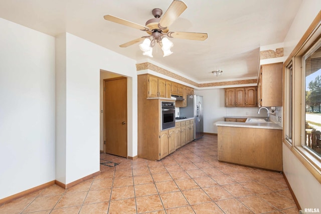 kitchen featuring a sink, appliances with stainless steel finishes, light countertops, light tile patterned floors, and baseboards