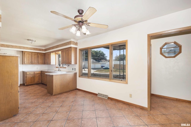 kitchen with light tile patterned floors, visible vents, a peninsula, and light countertops